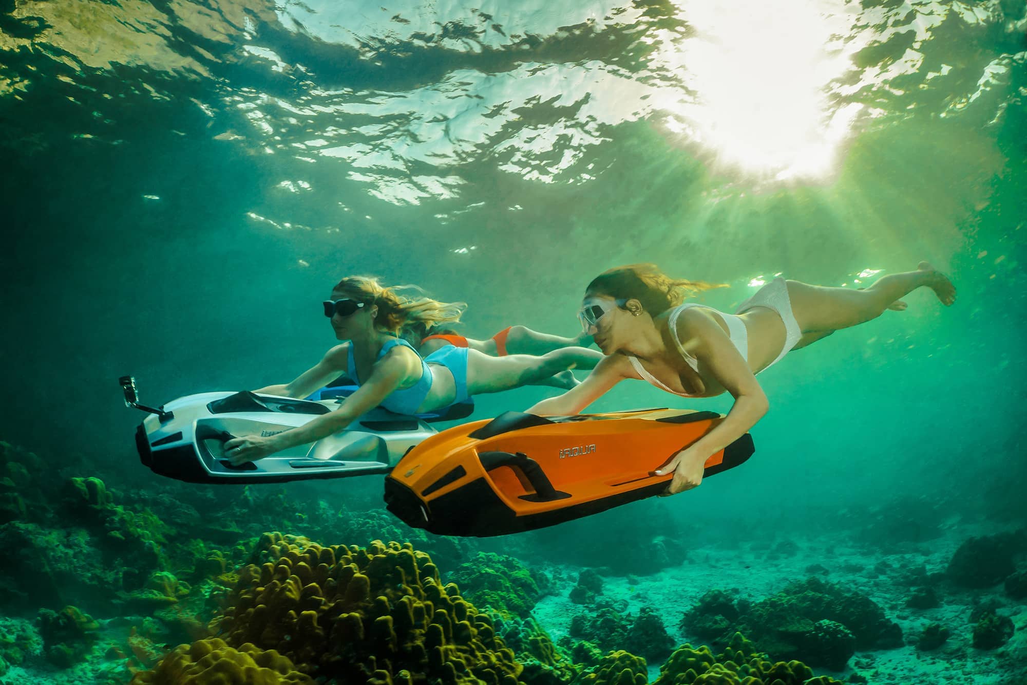 2 γυναίκες που κολυμπούν με σκούτερ iAqua εξερευνώντας τον ωκεανό.