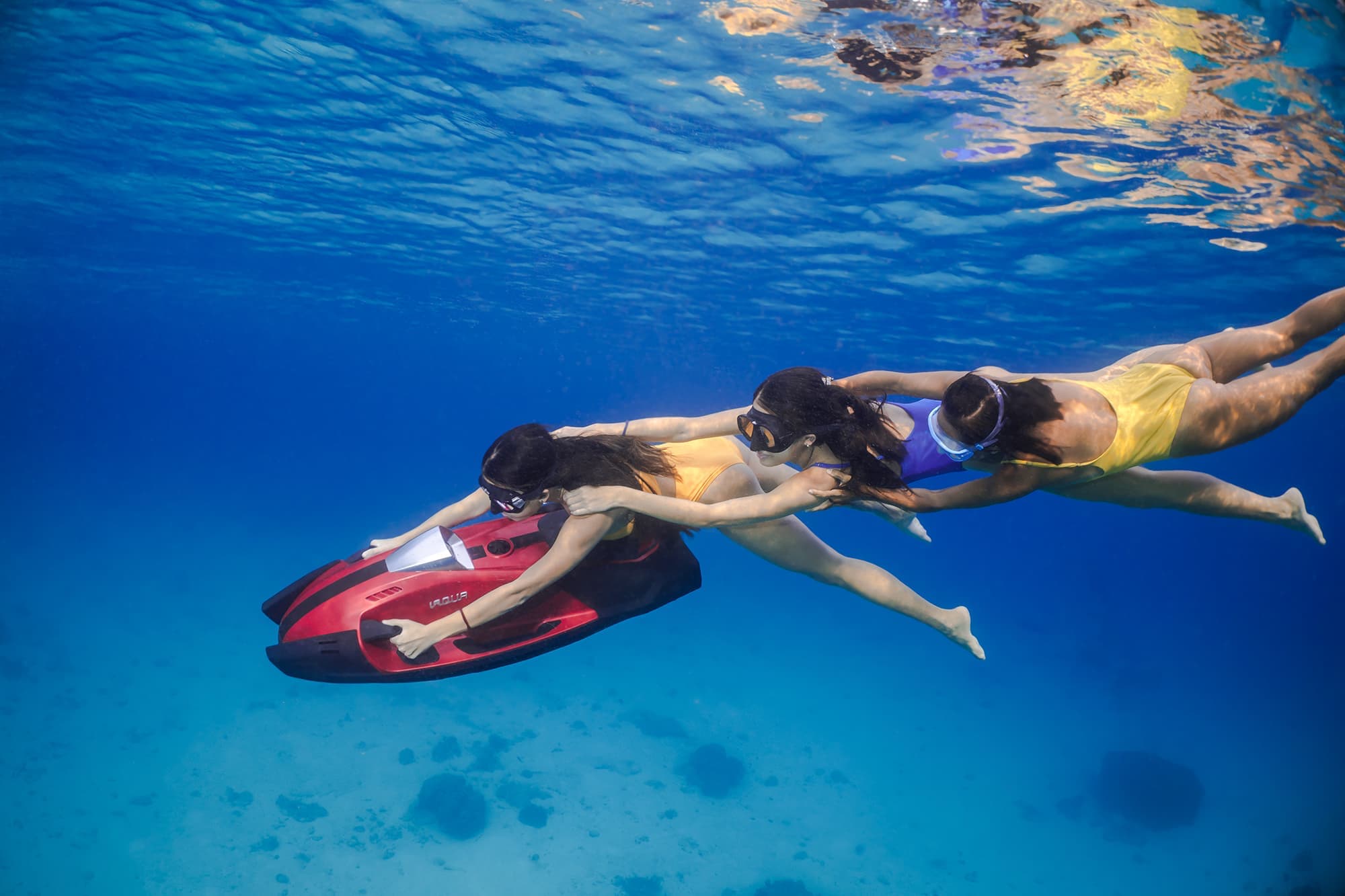 Três mulheres usando um brinquedo aquático iAqua explorando o oceano.